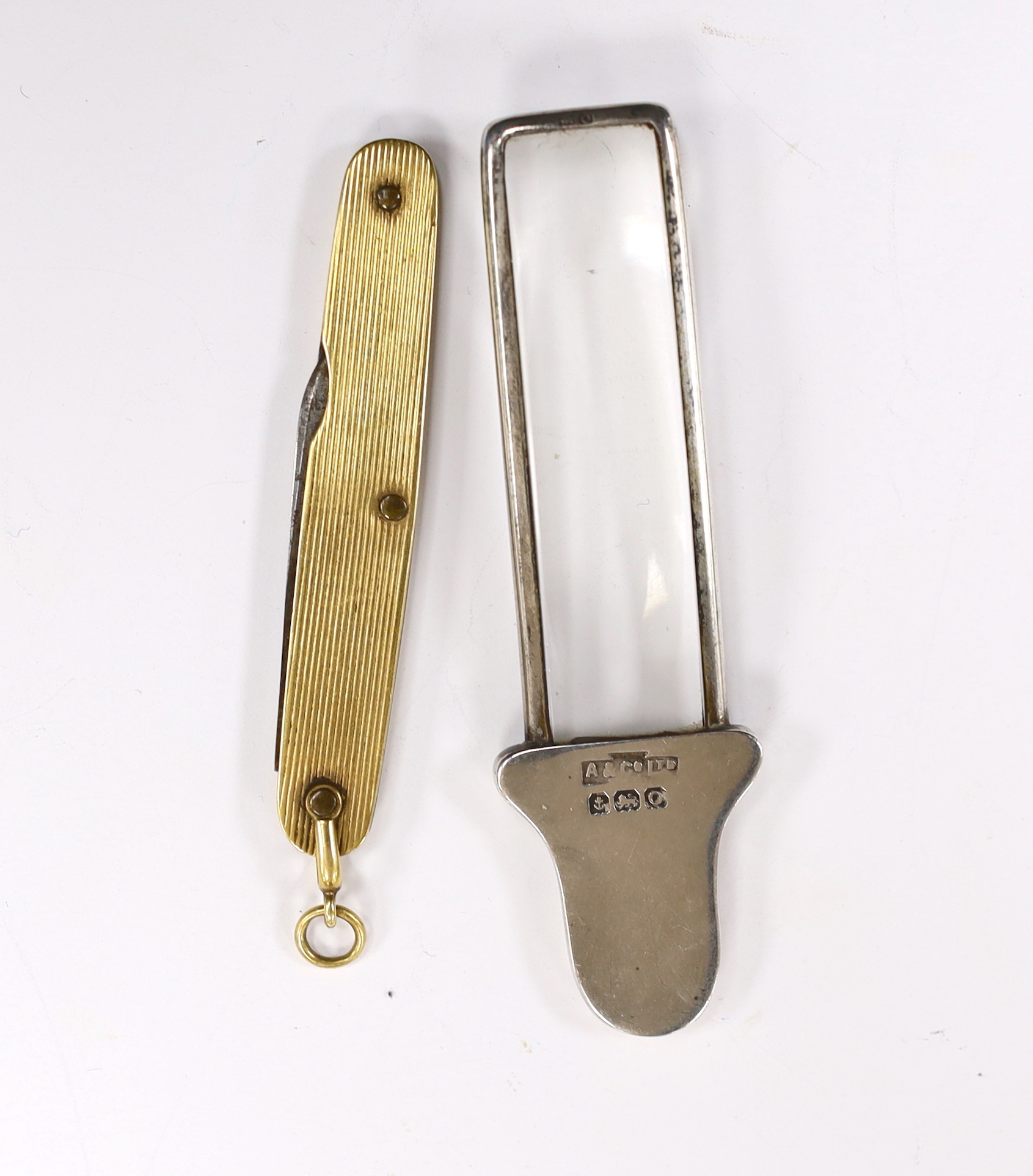 A small George V silver handled magnifying glass, by Asprey & Co Ltd, Birmingham, 1913, 85, together with a reeded yellow metal mounted penknife, retailed by Asprey.